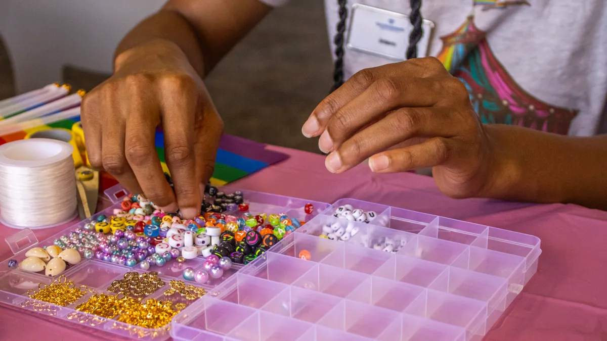 Hands sorting colorful beads into a compartment tray