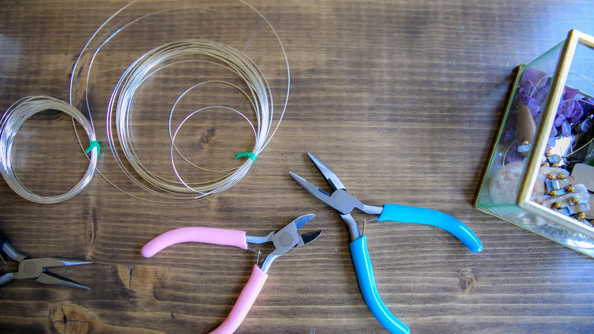 Wire coils and jewelry pliers on a wooden table