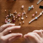 How to Make a Beaded Necklace Hands arranging beads and a beaded necklace on a worktable