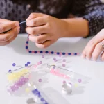 How to Make a Simple Beaded Bracelet Hands making beaded bracelets at a craft table