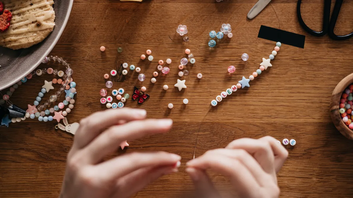 Hands stringing colorful beads on cord